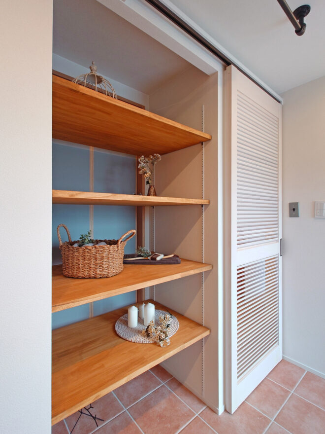 《洗面脱衣室》外の廊下側からも取り出しできる収納棚。扉は可動式ルーバーになっていて、バルコニーに出入りできるドアから入る光を暗い廊下に取り込むことが可能です。